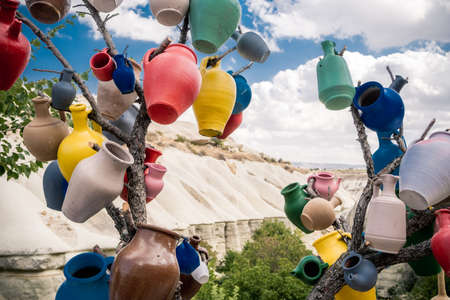 Colorful ceramic vases hanging on tree branch on mountain background in Turkeyの写真素材