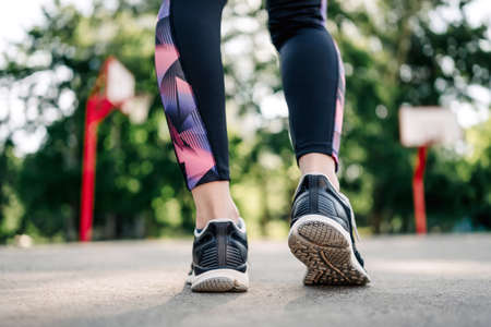 Closeup view on Young girl woman legs wearing sport leggings and shoes sneakers during exercising at...