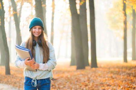 Happy school girl in autumn parkの写真素材