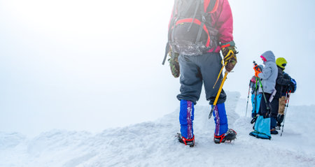 Tourists hiking snowy mountain in winterの写真素材