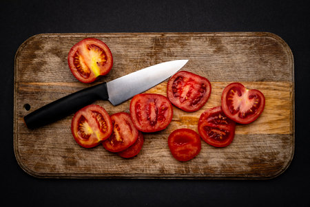 Sliced cherry tomatoes with knife on wooden board on background with copyspace. Healthy organic pomodoro vegetable for bruschetta view from aboveの写真素材