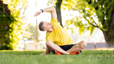 Man doing morning yoga at park outdoors in summer time. Guy during fitness stretching at nature in...