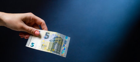 Hand holding five euro banknote after money exchange. European currency in cash as symbol of successの写真素材