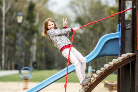 Funny little girl playing on the playground with ropeの写真素材