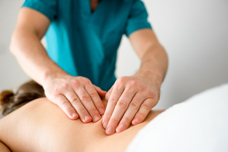 Girl during back massage lying in spa salon clinic. Masseur hands doing care body therapy procedure for young woman wellness and relaxation.の写真素材