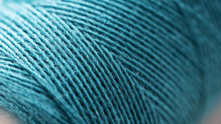 Blue sewing thread in spool for sew hobby closeup. Macro bobbin object for clothing repair
