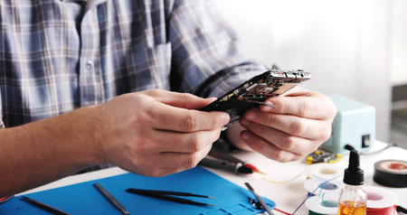 Service Technician Inspects Old Smartphone With Broken Screen In Service Workshopの写真素材