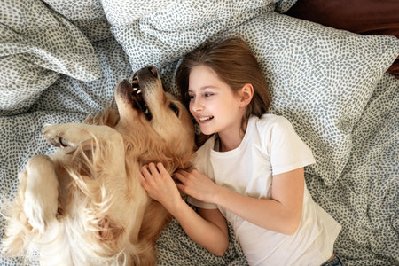 Cute Little Girl Playing With Golden Retriever Dog In Bedの写真素材
