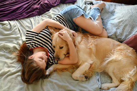 Cute Girl Playing With Golden Retriever Dog In Bedの写真素材