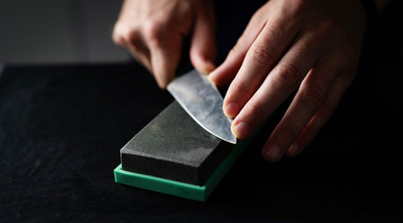 Close Up Of A Male Hands Sharpening Kitchen Knife With Whetstone, Using Water Sharpening Stone At Homeの写真素材