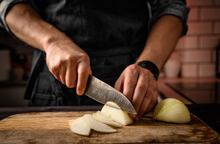Chief hands cutting onion at kitchen. Restaurant professional sliced vegetable on wooden boardの写真素材