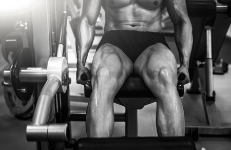 Strong muscular bodybuilder doing legs with machine in a modern gymの写真素材