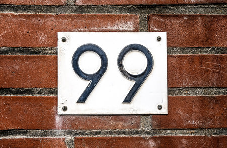 Address sign on residential building brick wall with number ninety nine. House identification...