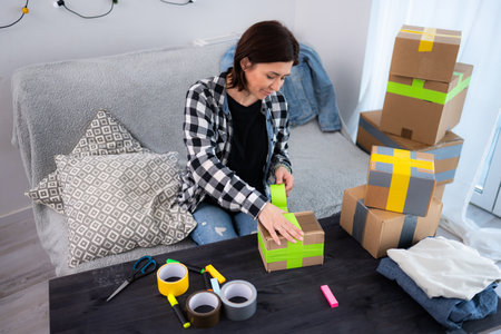 Girl Packs A Cardboard Box At Home While Packaging Handmade Productsの写真素材