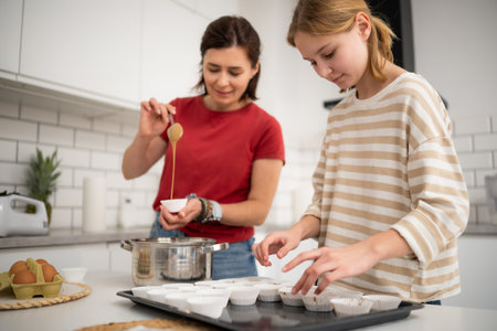 Happy Little Girl And Mother Baking Muffins In The Kitchenの写真素材