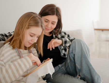 Mother Teaches Embroidery On A Hoop To Little Girl, Holding Thread With A Needle And An Embroidery Hoopの写真素材