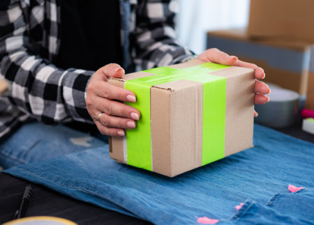 Girl Prepares A Cardboard Box For Shipping With Handmade Clothes