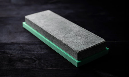 Sharpening Stone For Kitchen Knives Lies On Dark Tableの写真素材