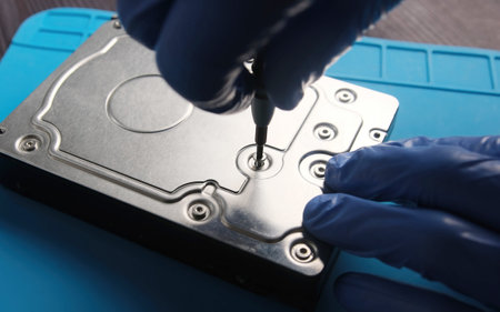 serviceman disassembling hard data disk drive to repair in service center