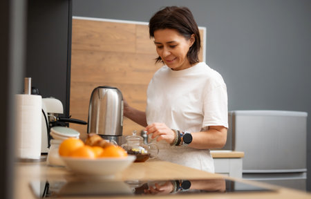 Young Woman Brewing Black Coffee In A Pot In The Kitchen In The Morningの写真素材