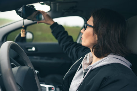 Female Driver In A Car Adjusts The Rearview Mirrorの写真素材