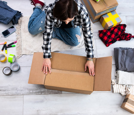 Girl Preparing For Moving By Packing Cardboard Boxesの写真素材