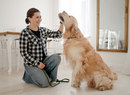 Cute Girl Petting Adorable Golden Retriever Dog On The Kitchen Floorの写真素材