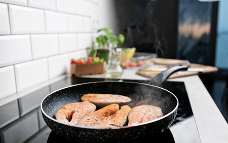 Red Fish Salmon Frying And Steaming In A Pan On The Kitchen Stoveの写真素材