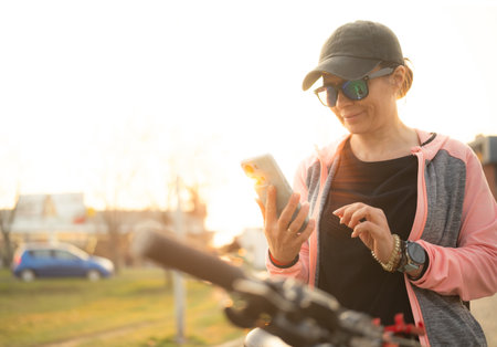 Woman Checking Bike Route On A Smartphone With Gps Map on city streetの写真素材
