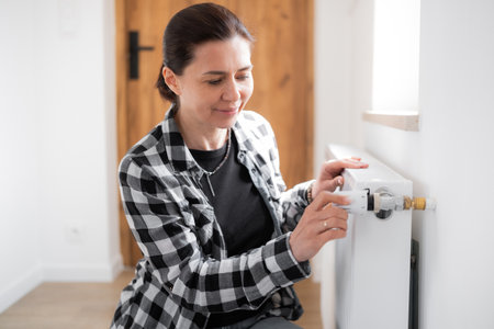Girl Adjusting Heater Temperature By Rotating The Regulatorの写真素材