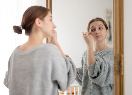 Young Girl Removes Makeup With A Makeup Removal Liquid And Cotton Pad In Front Of The Mirror
