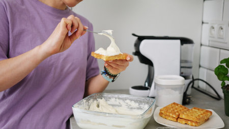 Woman Spreading Whipped Cream On Belgian Waffleの写真素材
