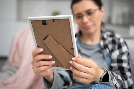 Girl Holds A Photo Frame And Looks At An Old Family Photograph