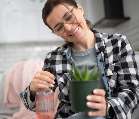Girl Wetting Home Pot Plant At The Kitchenの写真素材