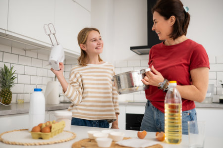 Happy Little Girl And Mother Baking And Having Fun Playing With A Mixer In The Kitchenの写真素材