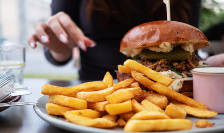 Girl Eating Fried Potatoes And A Meat Burger In An Outdoor Restaurant
