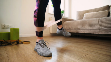 Girl Doing Fitness Exercises With A Rubber Resistance Band Training Legs At Home