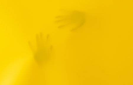 Silhouettes Of Kid's Hands Behind Yellow Fabricの写真素材