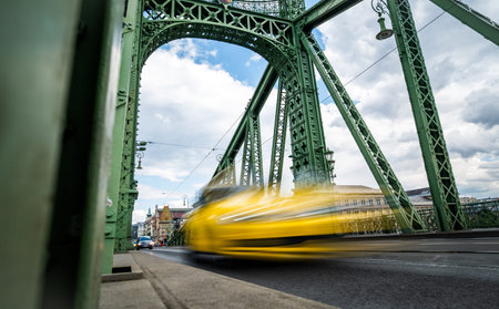 Yellow Taxi Car Drives Fast By A Retro Bridge In The Rushing City