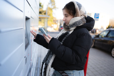 Young Girl Opens Outdoor Parcel Locker On A Street Using A Smartphone