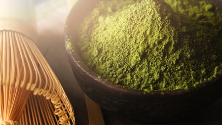 Matcha green tea powder in a bowl with a whisk for whipping