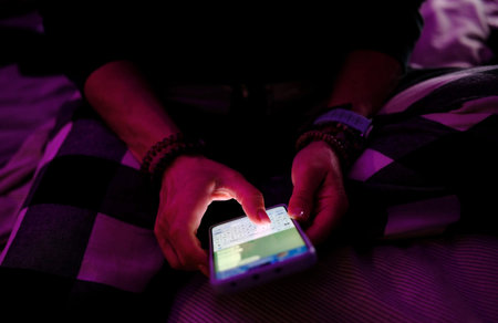 Girl Sitting In Bed Typing Text With Emoji In Messenger On Smartphone At Night In A Dark Room