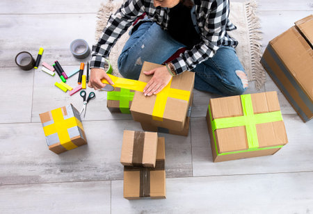 Girl Packing Cardboard Boxes And Sealing Them With Colorful Tapes