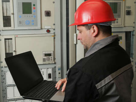 Engineer reading data with laptop in power plant
