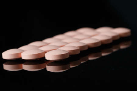 Group of pink pills on black with reflectionの写真素材