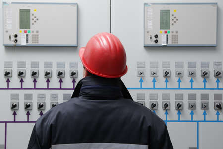 Technician reading instruments in power plant control center