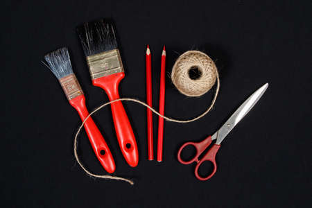 Packthread  two red  paint  brushes  crayons and   scissors on black background