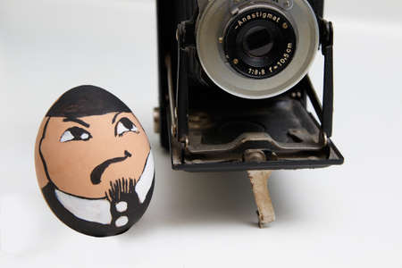 Egg face photographer with old retro camera on white