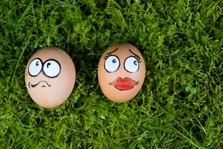 Fractious boy and girl egg face on green grassの写真素材
