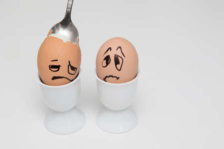Two frightened egg face in eggcup on white
